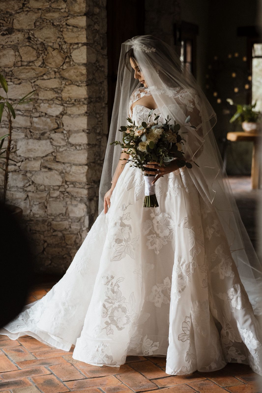 Novia de cuerpo completo con vestido de aplicaciones florales, velo y ramo