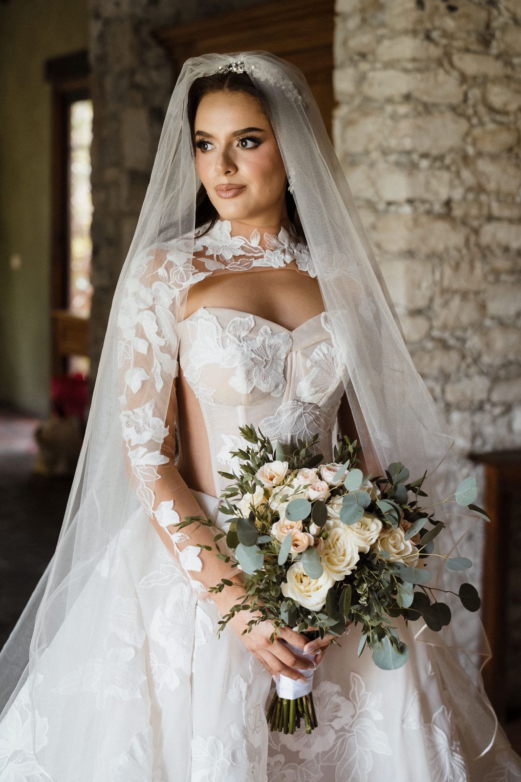 Retrato de novia con velo, encaje floral y ramo de rosas